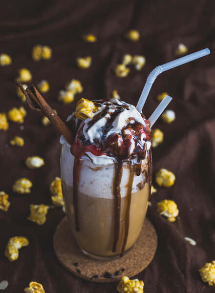 Glass of coffee with sour cream, caramel popcorn and chocolate