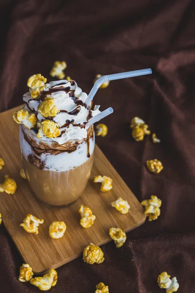 Szklanka kawy z kwaśną śmietaną, popcorn karmelowy i czekolada — Zdjęcie stockowe