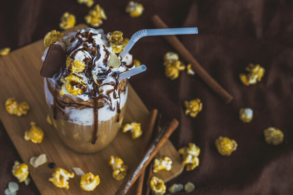 Glass of coffee with sour cream, caramel popcorn and chocolate