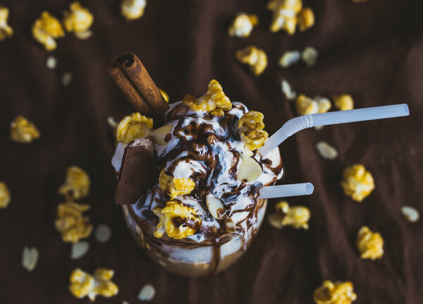 Glass of coffee with sour cream, caramel popcorn and chocolate