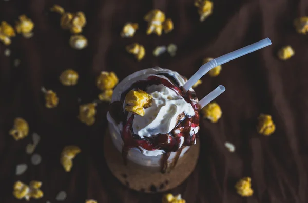 Glas kaffe med gräddfil, karamell popcorn och choklad — Stockfoto