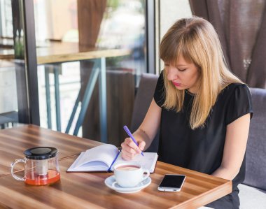 çay içme ve iş kağıtları ile çalışan kadın