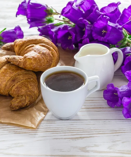 Чашка кофе, круассаны, банка молока и цветы сирени — стоковое фото