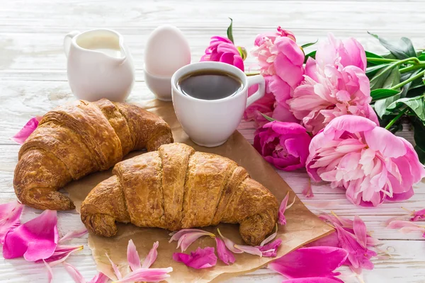 Cup of coffee, croissants, milk jar and peonies flowers — Stock Photo, Image