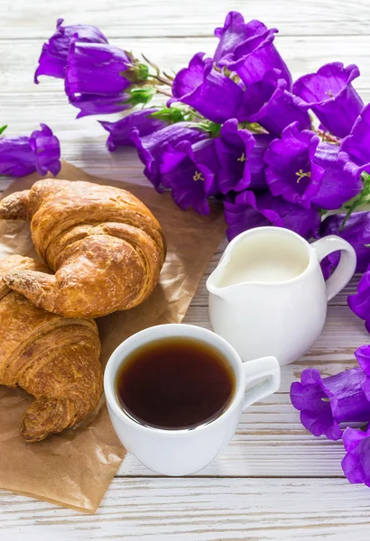 Чашка кофе, круассаны, банка молока и цветы сирени — стоковое фото