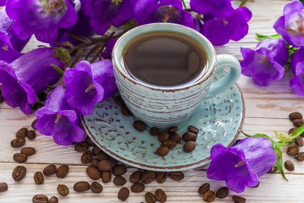 Taza de café, granos de café y flores lila — Foto de Stock