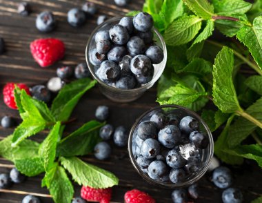 Yaban mersini, ahududu ve nane, siyah ahşap masa. 