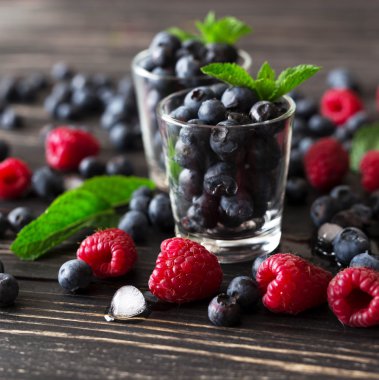 Yaban mersini, ahududu ve nane, siyah ahşap masa. 