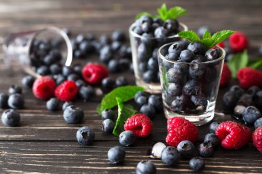 Yaban mersini, ahududu ve nane, siyah ahşap masa. 