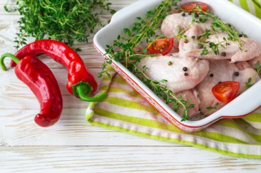 Çiğ tavuk kanatları kekik, kırmızı biber, biber ve domates ile 