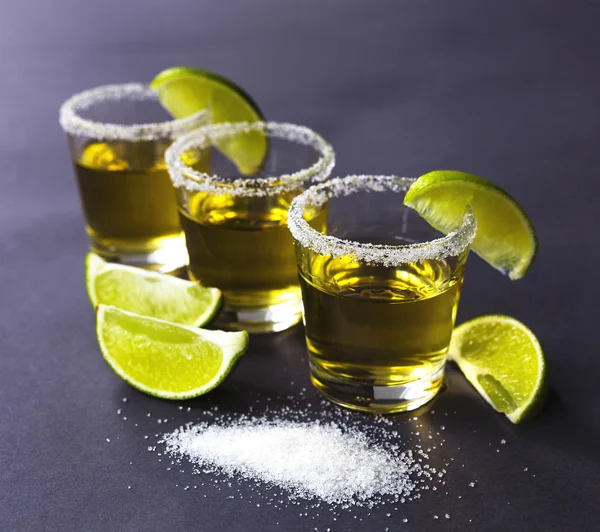 Gold tequila with lime and salt on dark table — Stock Photo, Image