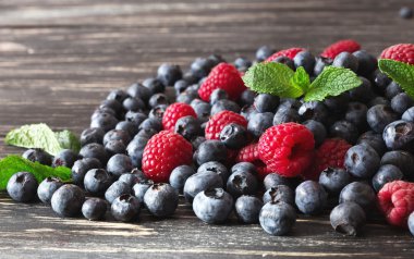 Yaban mersini, ahududu ve nane, siyah ahşap masa. 