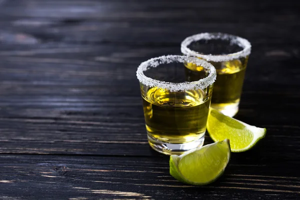 Gold tequila with lime and salt on dark table — Stock Photo, Image