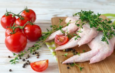 Çiğ tavuk kanatları kekik, kırmızı biber, biber ve domates ile 