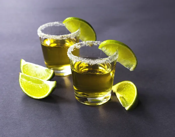 Gold tequila with lime and salt on dark table — Stock Photo, Image