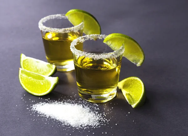 Gold tequila with lime and salt on dark table — Stock Photo, Image