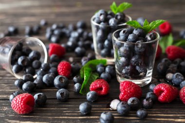 Yaban mersini, ahududu ve nane, siyah ahşap masa. 