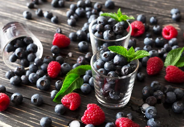Blueberries, raspberries and mint at black wooden table. — Stock Photo, Image