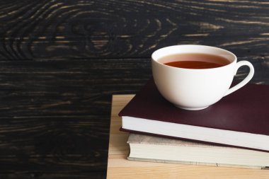 Fincan sıcak çay ve ahşap masa kitap