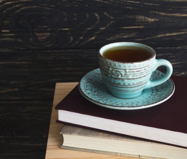 Fincan sıcak çay ve ahşap masa kitap