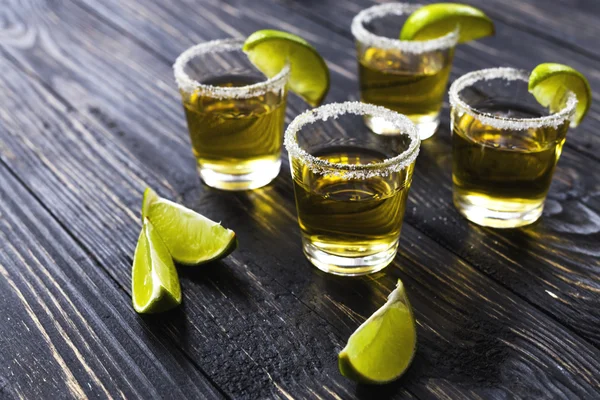 Gold tequila with lime and salt on dark table — Stock Photo, Image