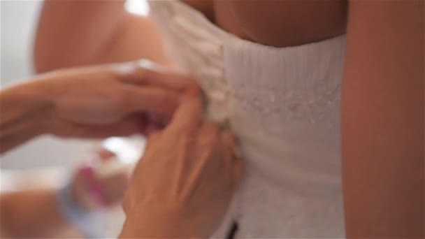 Družička je šněrování bílé svatební šaty pro krásnou nevěstu, příprava svatební — Stock video