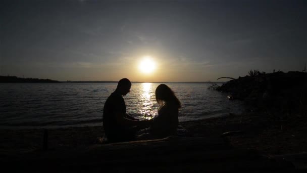 Un par esperando a un bebé sentado en la orilla del río. Feliz embarazo pareja — Vídeos de Stock