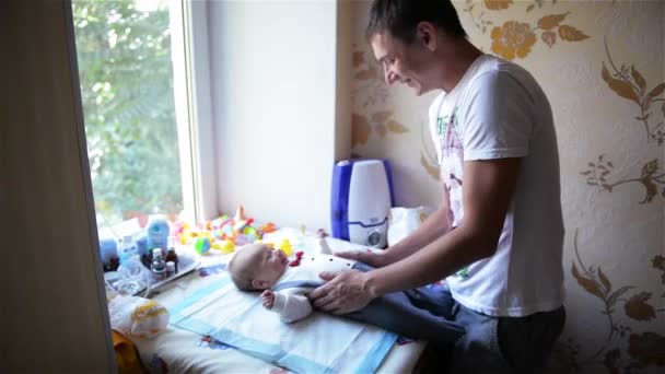 Bébé riant, Jeune père jouant avec son bébé, Bébé s'allonge sur une planche à langer — Video