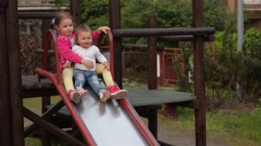 Çok eğlenceli oyun alanında slayt aşağı sürme sırasında iki küçük şirin kız orgazm