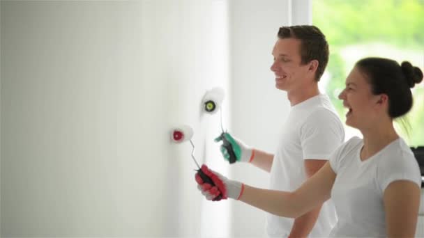 Jovem casal decorar seu novo apartamento.Eles estão pintando a parede — Vídeo de Stock