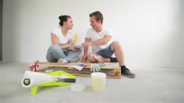 Genç bir çift yeni bir ev taşıma. Karı ve koca bir duvar için bir renk seçme