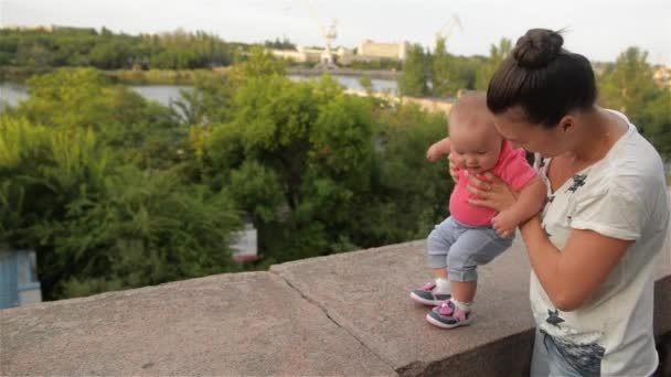 Liten flicka lära sig gå med sin mamma, första stegen, park, solig dag — Stockvideo