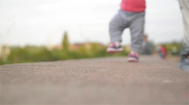 Küçük kız onun annesi, ilk adımları, park, güneşli gün ile yürümeyi öğrenme