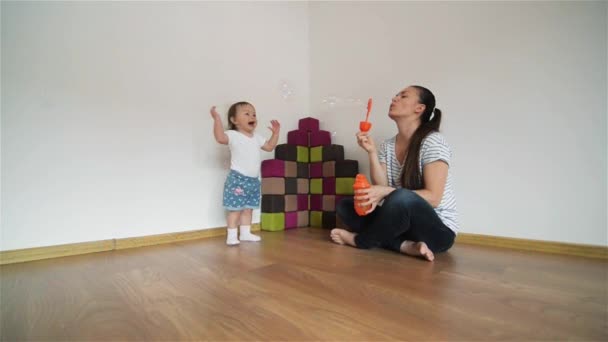 Jonge moeder waait bubbels voor zijn dochter, het meisje lachen en plezier — Stockvideo