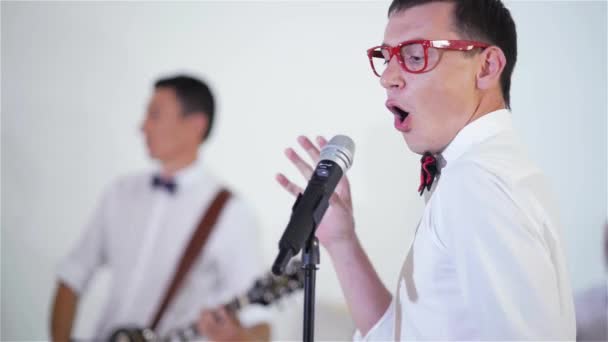 Забавный молодой певец поет песню в микрофоне, крупным планом — стоковое видео