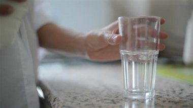 Woman pouring milk in a glass in the kitchen, closeup