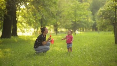 Anne ve kız açık sabun köpüğü üfleme. Anne-baba ve çocuk parkında eğleniyor.