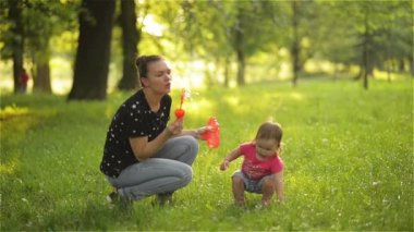 Anne ve kız açık sabun köpüğü üfleme. Anne-baba ve çocuk parkında eğleniyor.