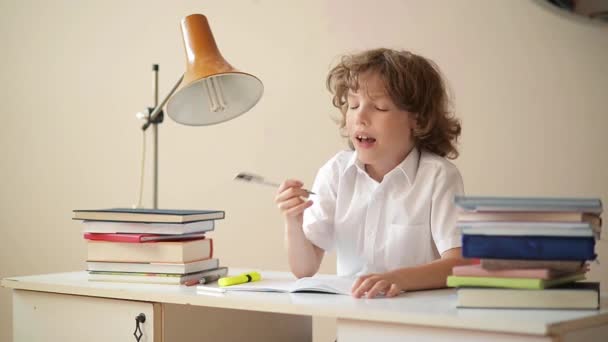 Liten pojke studera eller göra hemuppgifter, skolpojke studerar med anteckningsboken och böcker på bord — Stockvideo