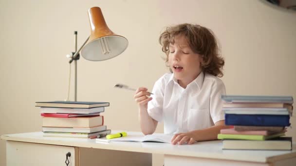 Ragazzino che studia o fa lavoro a casa, scolaro che studia con taccuino e libri sul tavolo — Video Stock