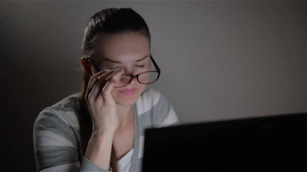 Junge müde Geschäftsfrau mit Kopfschmerzen sitzt am Computer am Arbeitsplatz - Überstunden in der Nacht — Stockvideo