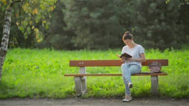 Parkta bir bankta oturmuş ve genç kadın bir bankta rahatlatıcı bahçede, sınav hazırlama öğrenci kitap okumak güzel kadın