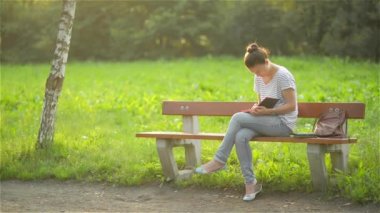 Güzel genç kadın bir günlük açık havada park, parkta bir bankta niteliğine sınava hazırlanıyor öğrenci kız öğrenci yazıyor