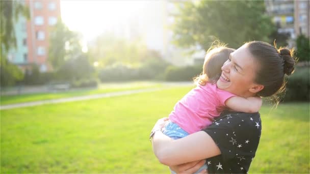 Anne ve çocuk sarılma ve doğada, mutlu neşeli aile açık eğleniyor. Anne ve bebek öpüşme, gülüyor ve sarılma — Stok video