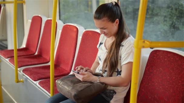 Красива молода жінка подорожує міським транспортом і використовує свій мобільний телефон. Жінка використовує смартфон у громадському транспорті — стокове відео