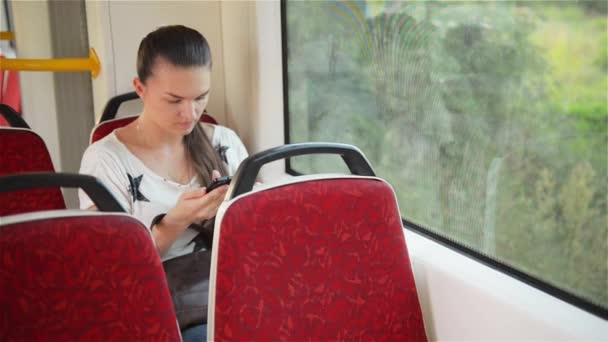 Jong meisje met behulp van slimme telefoon tijdens het rijden met de bus, mooie vrouw reizen in het stedelijk vervoer en het gebruik van haar mobiele telefoon — Stockvideo