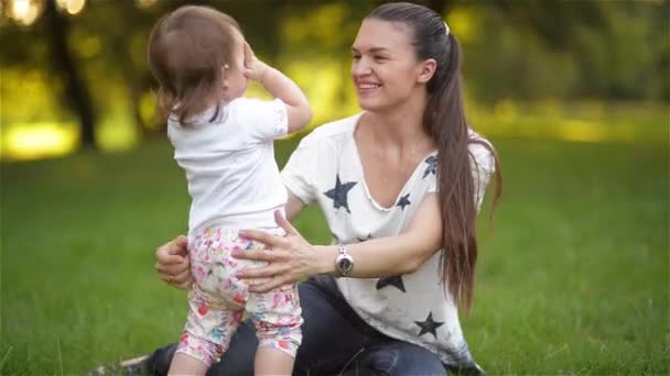 Madre e hija abrazándose en el amor jugando en el parque, mamá joven jugando con sus hijos en el jardín, familia feliz — Vídeos de Stock