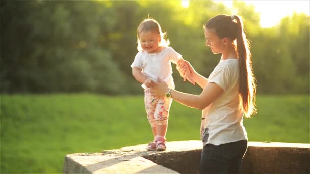 Mutter und Tochter spazieren in der Natur, schöne Mutter mit ihren kleinen Kindern an einem warmen Sommertag an der Hand im Park — Stockvideo