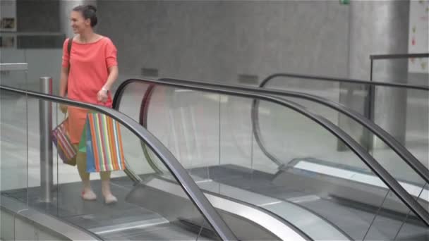 Dos chicas bajando las escaleras en escaleras mecánicas en el centro comercial, amigos están de compras en una tienda, mujeres haciendo compras en la tienda — Vídeo de stock