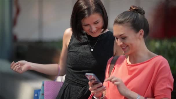 Розслабтеся після успішного досвіду покупок, молода дівчина з різнокольоровими сумками дивиться щось на вашому смартфоні . — стокове відео